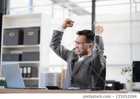 Happy male businessman celebrating success, raising hands in excitement 135052084