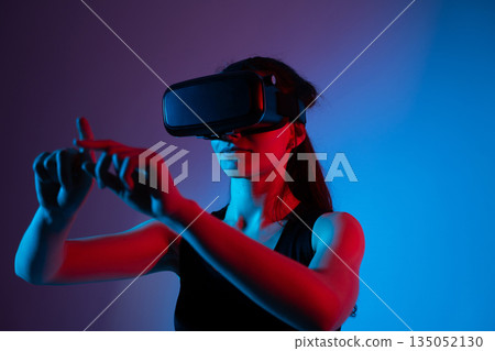 Female user wearing VR headset performing swipe gesture to navigate virtual interface Female user wearing VR headset performing swipe gesture to navigate virtual interface 135052130