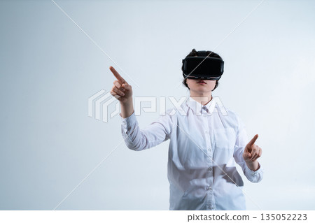 Woman controlling virtual reality system with both hands using advanced digital interface and motion tracking technology on white background Woman controlling virtual reality system with both hands using advanced digital interface and motion tracking technology on white background 135052223