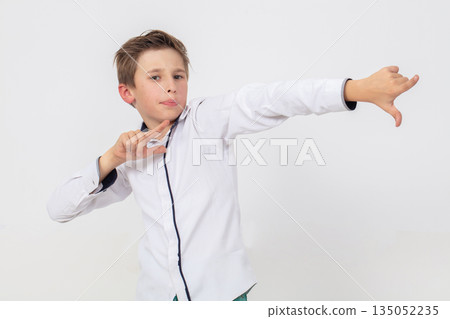 A school-age boy in a white shirt points his hand to the right on a white background A school-age boy in a white shirt points his hand to the right on a white background 135052235