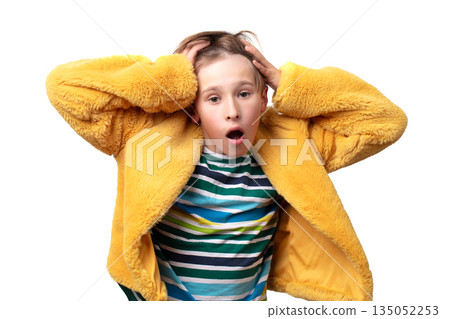 Teenage boy with surprise or indignation emotion posing in yellow jacket. He is wearing striped shirt. 135052253