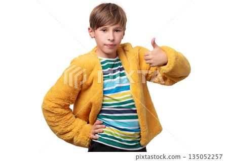 A boy in a yellow fluffy jacket and a striped shirt. He shows the sign of class. 135052257