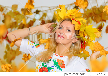 Beautiful middle-aged woman with a wreath of autumn leaves on her head. Beautiful middle-aged woman with a wreath of autumn leaves on her head. 135052767