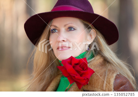 Elegant woman with a red rose enjoying nature in autumn 135052785