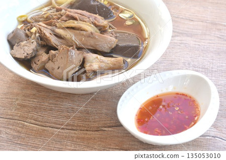 boiled slice duck meat with liver and blood in black soybean herb soup in bowl dipping spicy sour chili sauce boiled slice duck meat with liver and blood in black soybean herb soup in bowl dipping spicy sour chili sauce 135053010