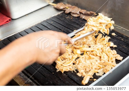 A person is cooking anticuchos on a grill 135053977