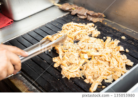 A person is cooking anticuchos on a grill 135053980