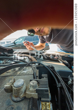 A man is working on a car engine A man is working on a car engine 135053989