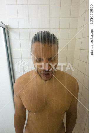 A man is standing in a shower with his head under the water A man is standing in a shower with his head under the water 135053990