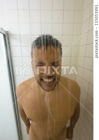 A man is standing in a shower with water spraying on his face A man is standing in a shower with water spraying on his face 135053991