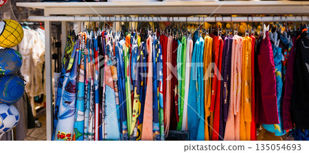 Colorful beach towels hanging at seaside market stall. Summer retail, tourism trade, vibrant textiles, and coastal vacation shopping experience Colorful beach towels hanging at seaside market stall. Summer retail, tourism trade, vibrant textiles, and coastal vacation shopping experience 135054693