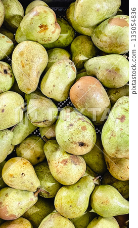 Close-up of fresh green organic pears with speckled skin piled at a local market or grocery store Close-up of fresh green organic pears with speckled skin piled at a local market or grocery store 135054836