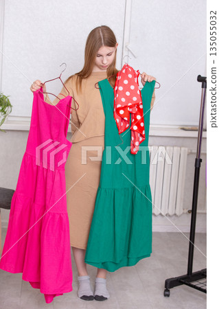 Choosing between a pink and a green dress while preparing for an event in a bright room Choosing between a pink and a green dress while preparing for an event in a bright room 135055032