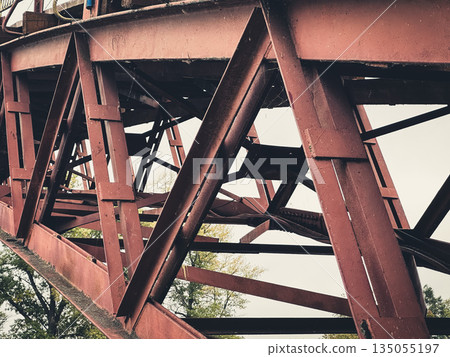 Close-up of a rusty metal bridge structure on an overcast day. Close-up of a rusty metal bridge structure on an overcast day. 135055197