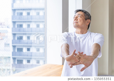 Senior man stretching by the window Senior man stretching by the window 135055351