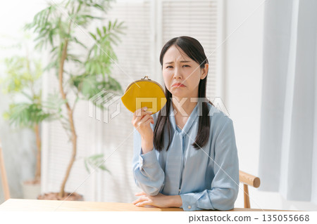 一位表情悲傷的女子手裡拿著錢包 一位表情悲傷的女子手裡拿著錢包 135055668