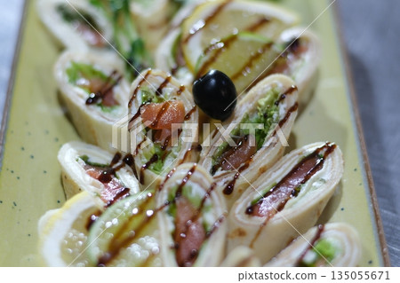Stuffed spinach roll appetizer Sliced diet pork roll stuffed with mushroooms, red bell pepper, spinach served with sauce. Brown wooden background. Top view, flat lay 135055671