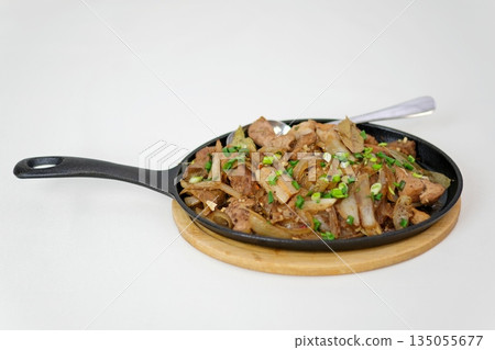 A stir fried beef with onion and green pepper sizzling on hot skillet, savory and aromatic A stir fried beef with onion and green pepper sizzling on hot skillet, savory and aromatic 135055677