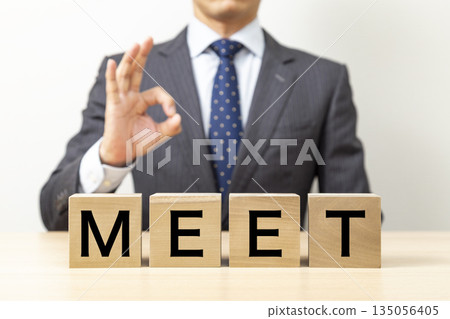 一位商人擺出「OK」的姿勢，旁邊立著一個寫著「MEET」的方塊。 135056405