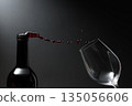 Red wine of rich color being poured from a bottle into a glass. 135056606