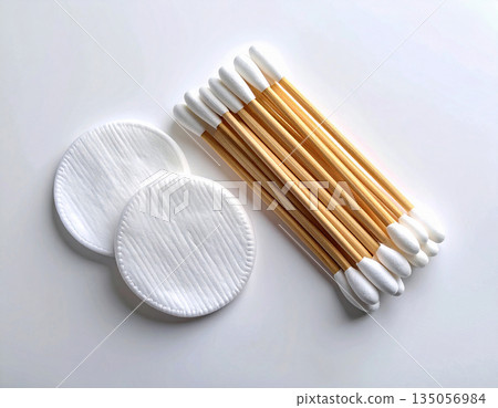 Hygiene cotton products. White cotton swabs and reusable cotton pads neatly stacked on a white background. Hygiene cotton products. White cotton swabs and reusable cotton pads neatly stacked on a white background. 135056984