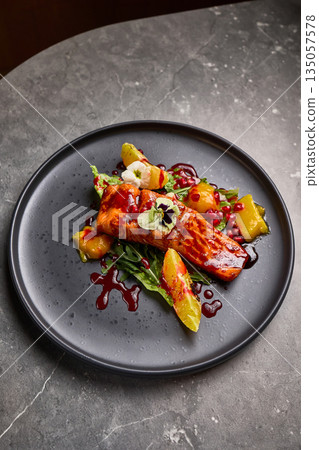 Gourmet Grilled Salmon with Citrus and Pomegranate Garnish on Dark Plate, Elegant Food Presentation Concept Gourmet Grilled Salmon with Citrus and Pomegranate Garnish on Dark Plate, Elegant Food Presentation Concept 135057578