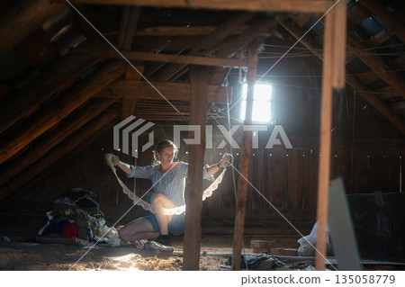 A woman sorts through things in an old attic. Antique finds. 135058779