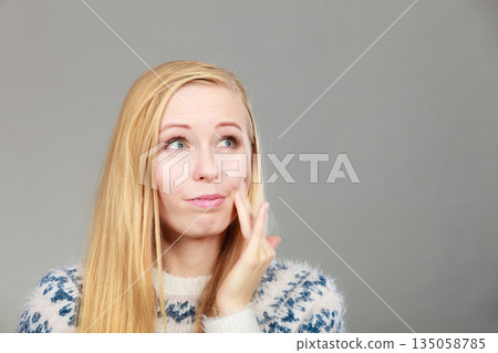 Woman having toothache touching her cheek Woman having toothache touching her cheek 135058785