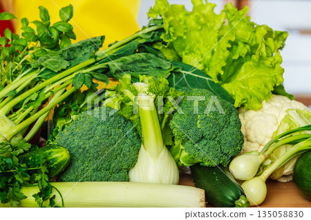 Many green vegetables on kitchen table 135058830