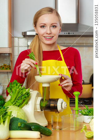 Woman in kitchen making vegetable smoothie juice 135058831