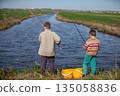 Boys children catch fish near the river. View from behind. 135058836