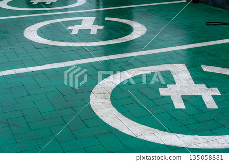 Bright green pavement showcases white circles indicating specific landing spots for helicopters, set in a lively city environment Bright green pavement showcases white circles indicating specific landing spots for helicopters, set in a lively city environment 135058881