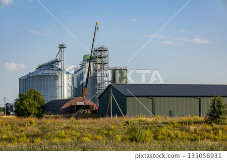 Large silos and a concrete granary stand proudly amid golden fields, showcasing the importance of grain storage in farming 135058931
