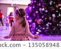 A little girl on the background of a Christmas tree blurred. A children's holiday at Christmas. 135058948