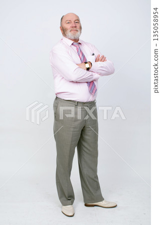 An elderly man in full height. He is dressed in a shirt with a tie and gray trousers. An elderly man in full height. He is dressed in a shirt with a tie and gray trousers. 135058954