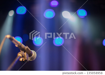 Microphone against blue stage lights. Beams from concert spotlights illuminate the microphone. 135058958