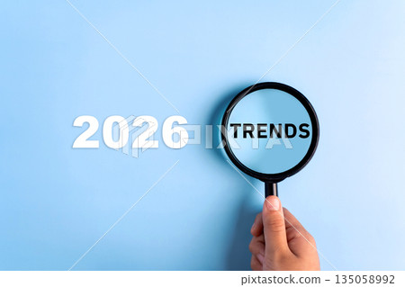 TRENDS text written on magnifying glasses, on blue background. New trends in business 2026 concept. 135058992