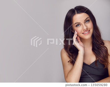 Beautiful brunette smiling woman with a long hair on a grey isolated background with a free copy space. Beautiful brunette smiling woman with a long hair on a grey isolated background with a free copy space. 135059280
