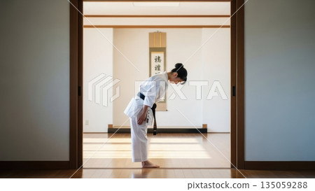 一位身著空手道服的日本女子在道場門口莊嚴地鞠躬。 135059288