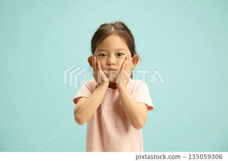 Shocked Five Year Old Child Girl Holding Face and Expresses Surprise Looking to Camera Stands on Blue Isolated Shocked Five Year Old Child Girl Holding Face and Expresses Surprise Looking to Camera Stands on Blue Isolated 135059306