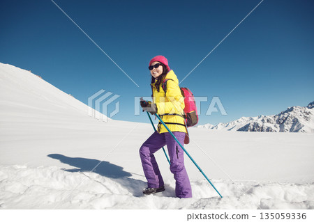 Solo Female Hiker Enjoying Sunny Winter Day in Snow-Covered Mountains 135059336