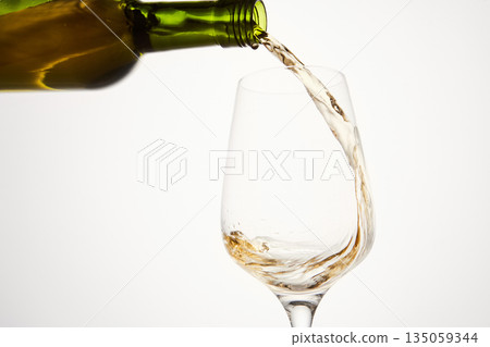 White wine pouring from green bottle, close up. 135059344
