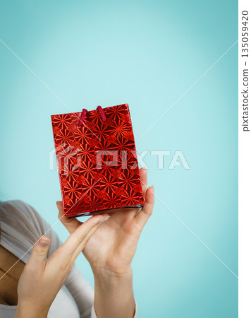 Woman holds red gift bag in hand Woman holds red gift bag in hand 135059420