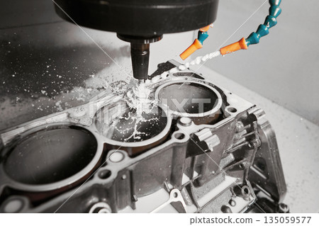 High precision cnc milling machine makes holes in the car engine with a coolant.  135059577