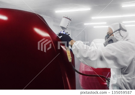 Professional car painter in chamber paints automobile bonnet. 135059587