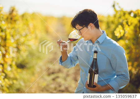 Professional Sommelier Tasting Red Wine on Vineyard Rows Background  135059637