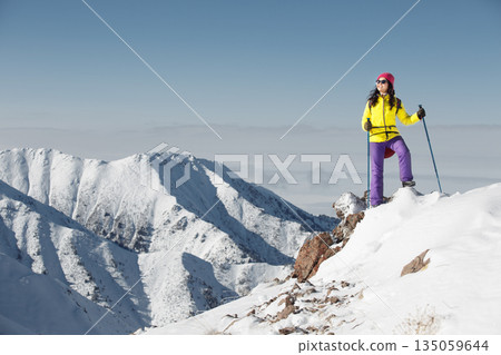 Tourist Hiker Standing on Snow Covered Mountain Summit Tourist Hiker Standing on Snow Covered Mountain Summit 135059644