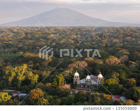 Forest with a building and a mountain in the background during sunset 135059800