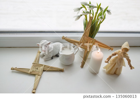Imbolc brigid's crosses celebration with snowdrops and candle 135060013