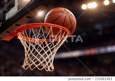 Close up of basketball just above rim in precise spinning motion highlighting successful free throw in action. moment of thrilling accuracy and scoring 135061463